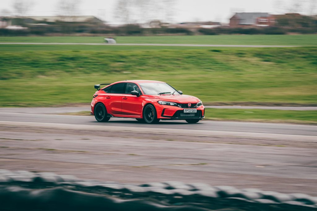 A red Honda Civic Type R speeding on an outdoor race track in Blyton, England.