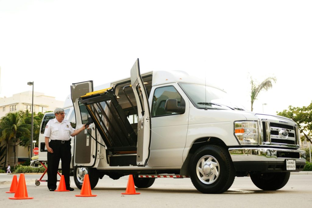 Security officer managing an accessible van with open lift platform, surrounded by traffic cones.